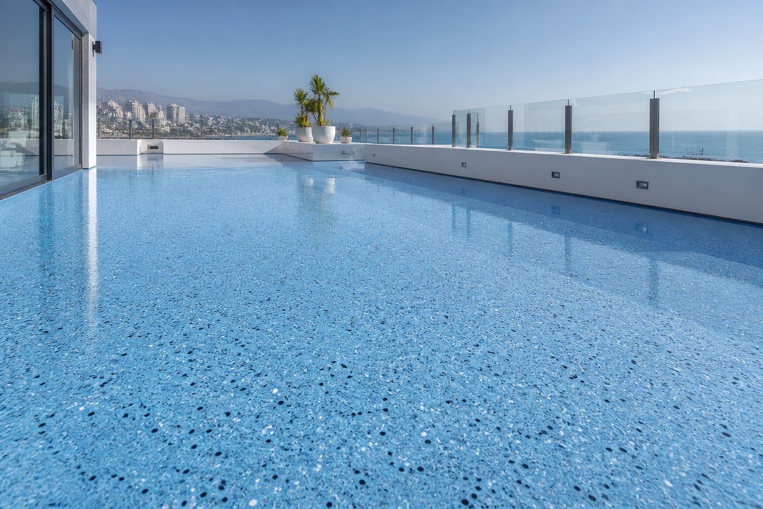 Polished sky-blue terrazzo flooring on an outdoor terrace with white parapet walls